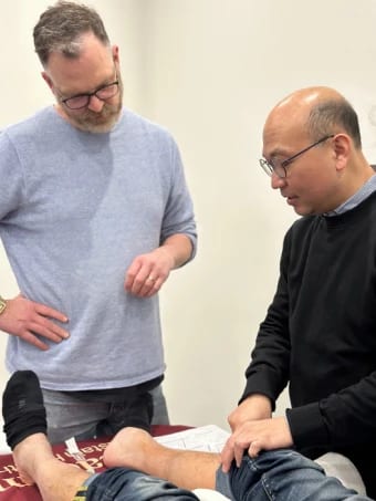 Dr Michael Chung guiding a participant needling a Tung point on the calf